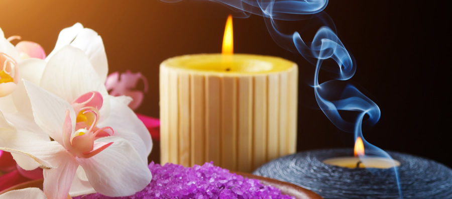 A candle and some purple rocks with smoke coming out of it.